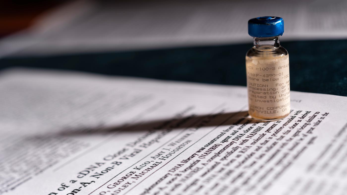 A vial of vaccine sits on documents about RNA