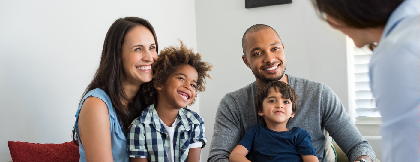 A family of four sitting on the couch looking at therapist