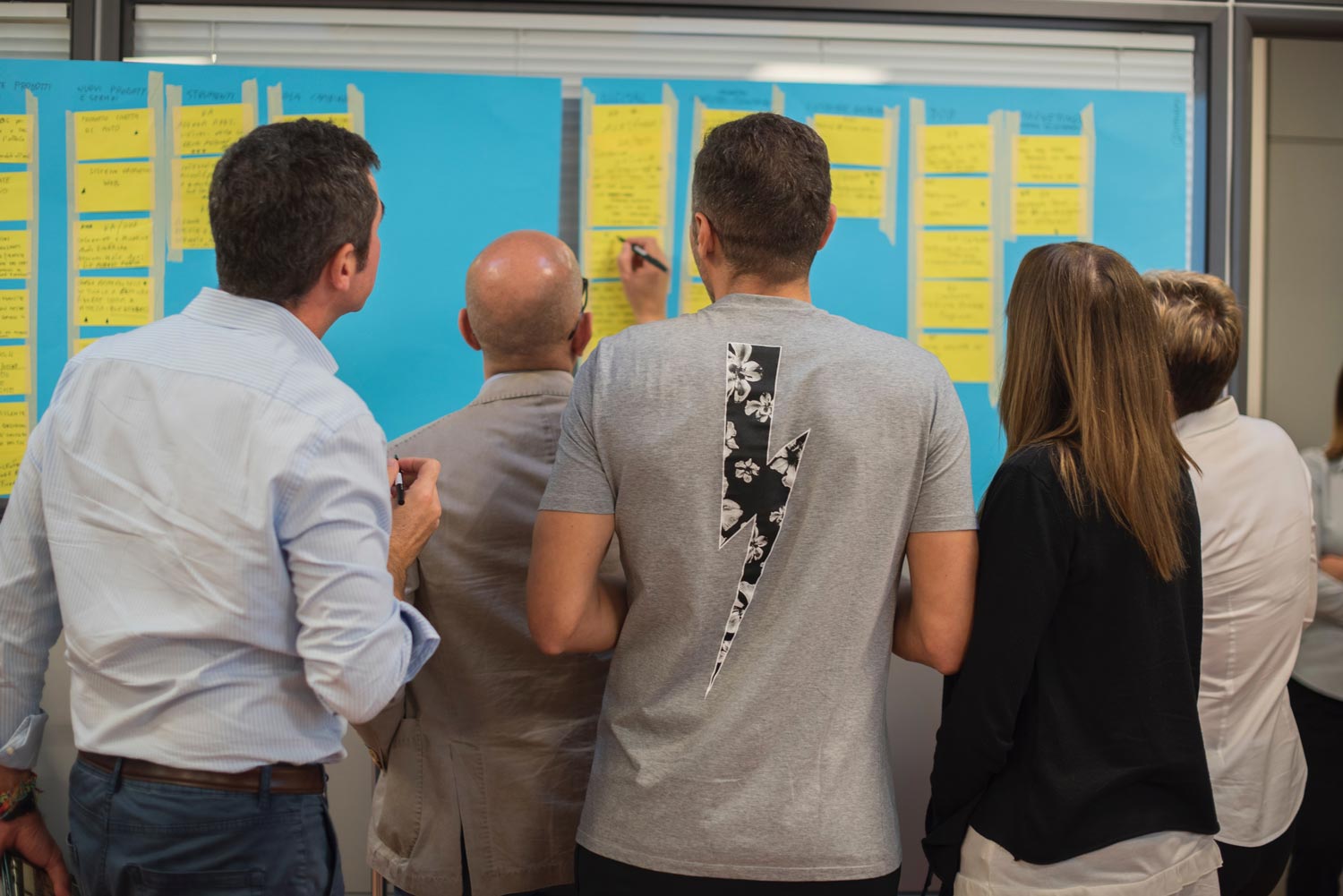 group of people working on cards stuck to a whiteboard together