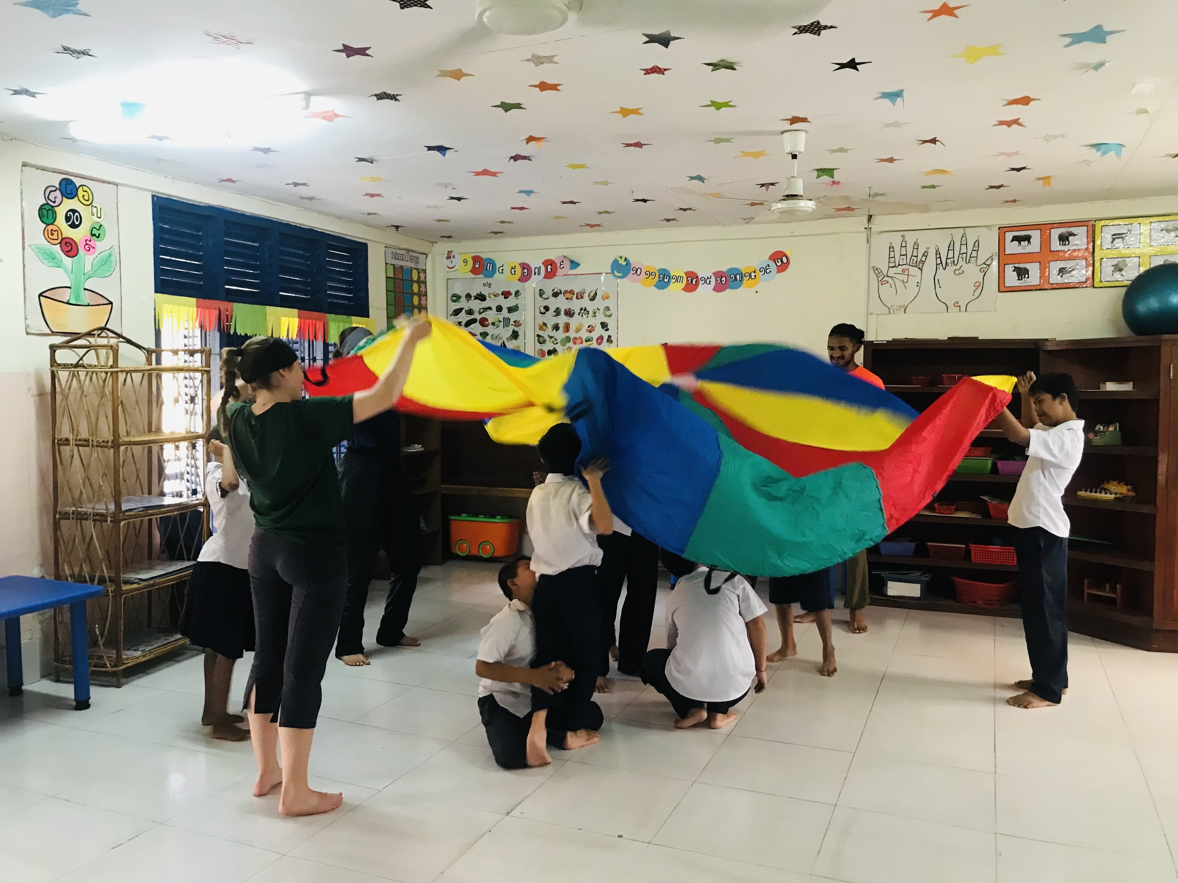 PAW participants Courtney Reid and Johann Gnanapragasam play parachute games with a primary class in Phnom Penh, Cambodia.