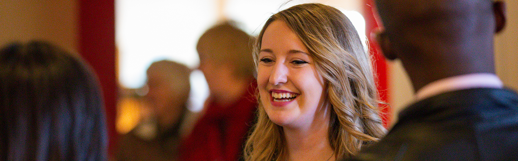 student laughs speaking to others in a crowded lobby