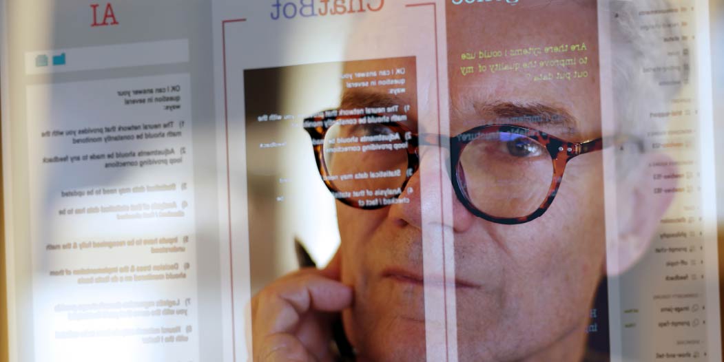 Staff member reflected in a computer monitor displaying text provided by a chatbot