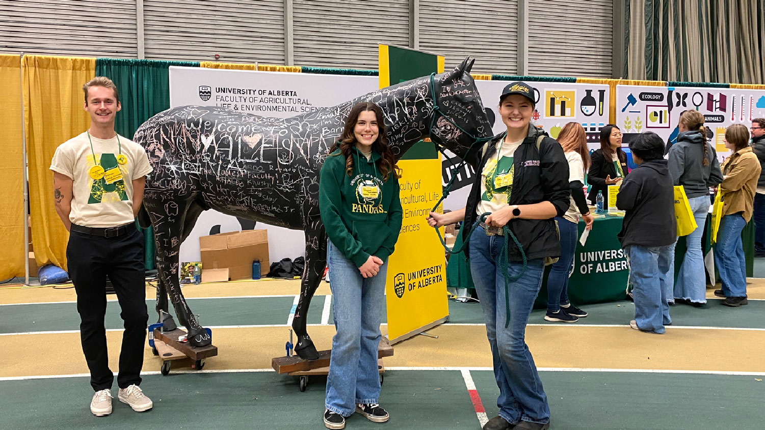 Three students around a painted horse statue at a fair in the butterdome