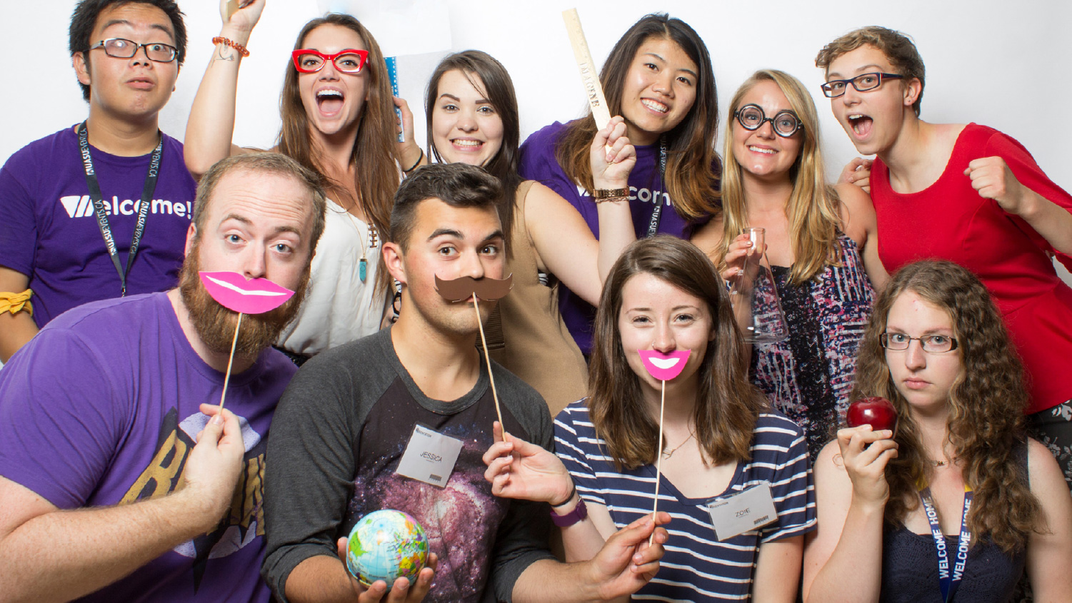 Group of students with photo booth props making excited faces