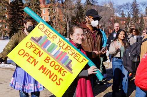 Woman holding sign that says Queer yourself open books open minds