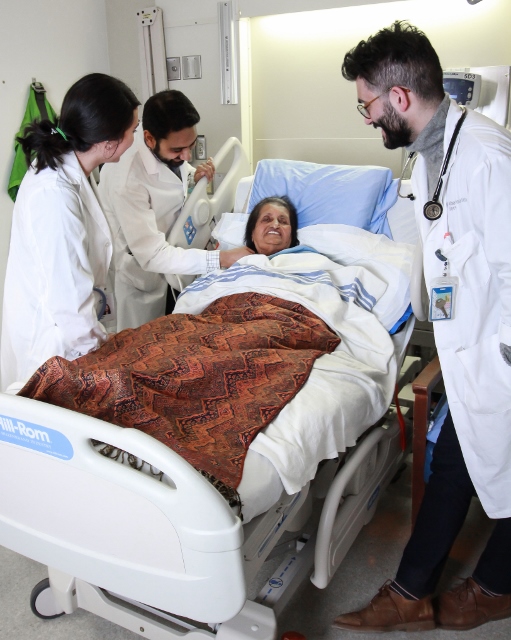 Daniels and students gather around happy patient in hospital bed