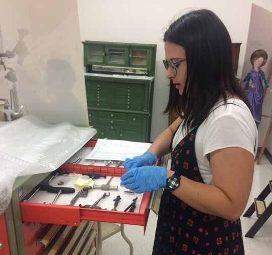 Jean holds dentistry tools in an extended red cabinet