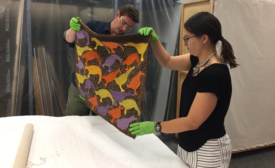 Jean holds up a colourful textile from the Art Collection