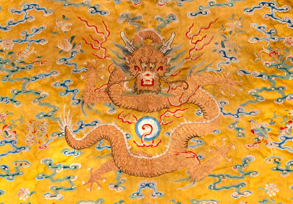 Golden embroidered dragon on a yellow textile