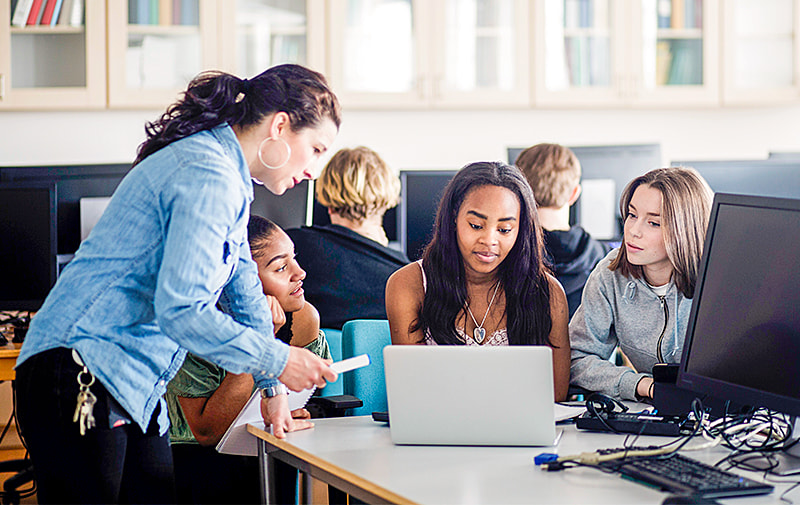 Teacher working with students on a computer