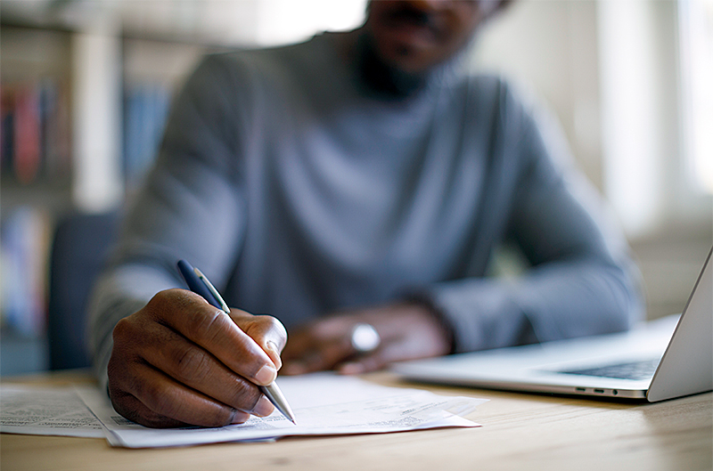  a man doing paperwork in front of his laptop