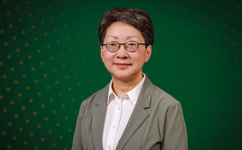 Photo of Verna Yiu standing against a green background.