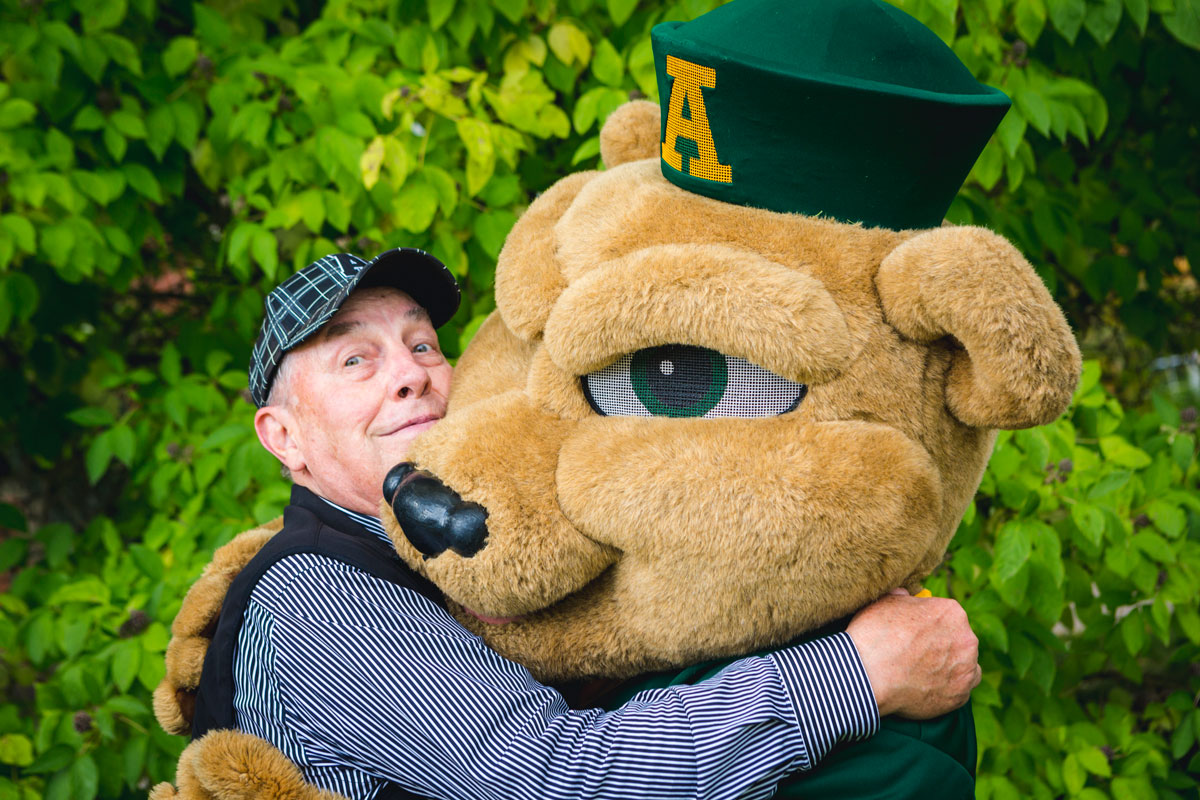 Chuck Moser hugging GUBA 40 years after he originally created the mascot