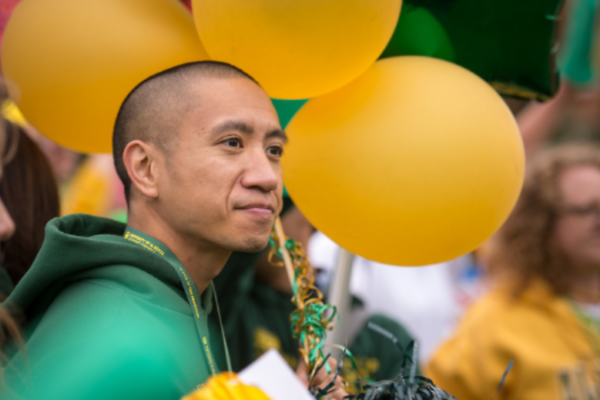 Man holding yellow and green balloons