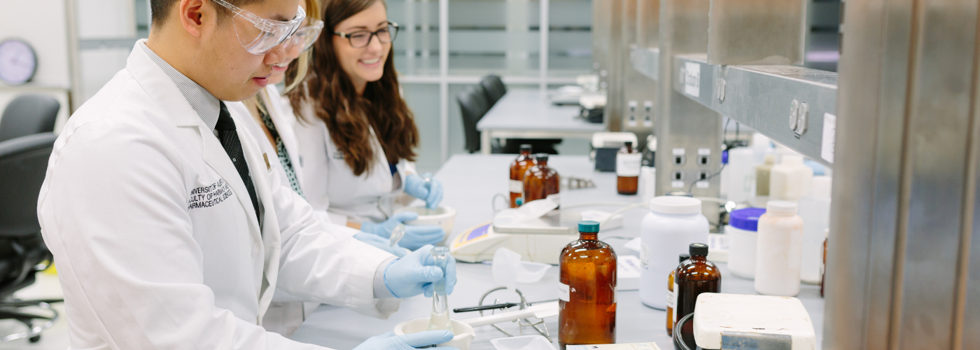 Three people in a lab using mortar and pestal