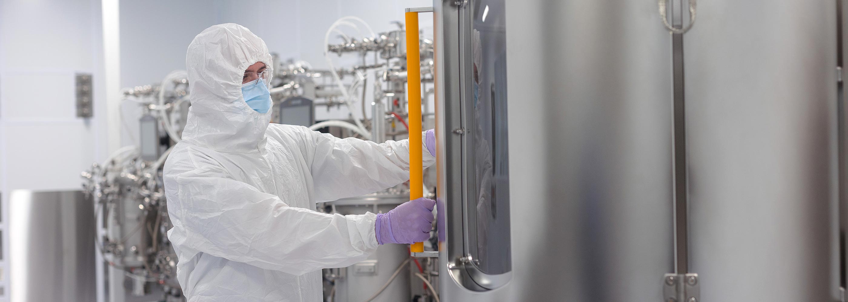 A researcher from Saskatchewan's Vaccine and Infectious Disease Organization (VIDO) wearing full protective equipment opening a bioreactor