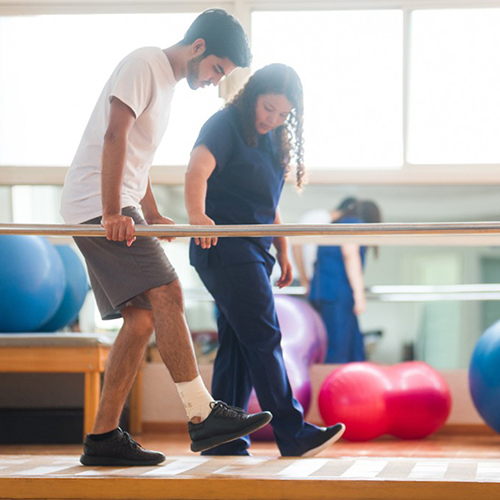 Physical therapy patient tries to walk with the help of a health professional