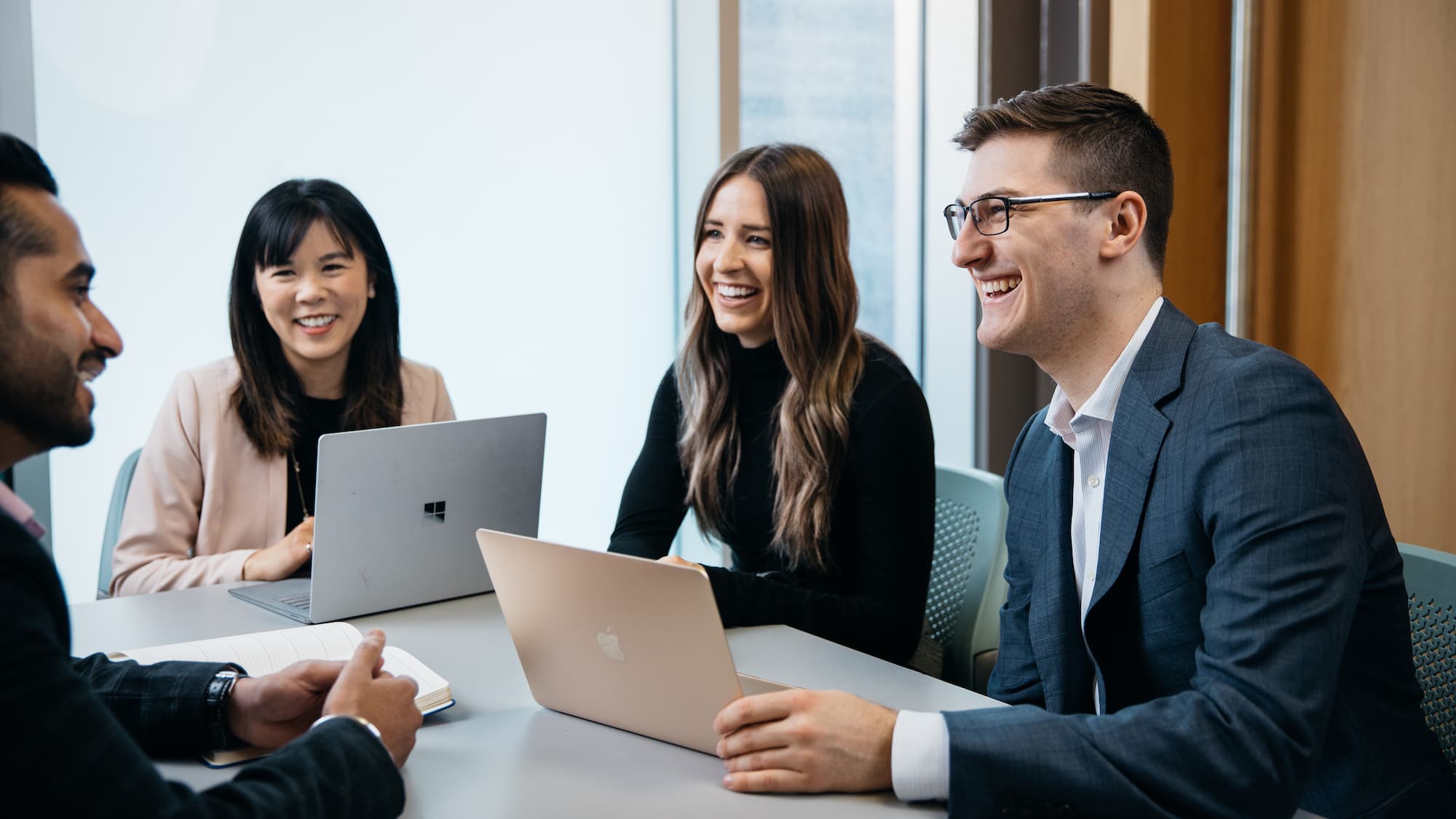 4 individuals smiling in a meeting