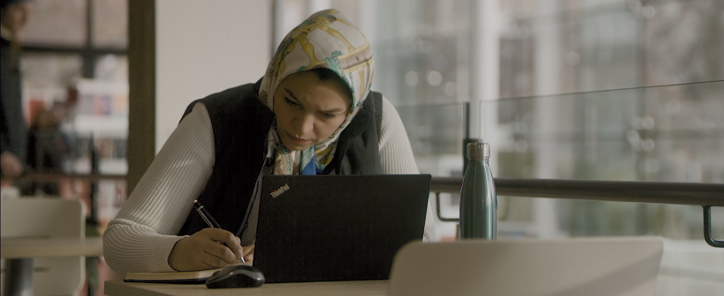 An individual writing at a table, looking focused