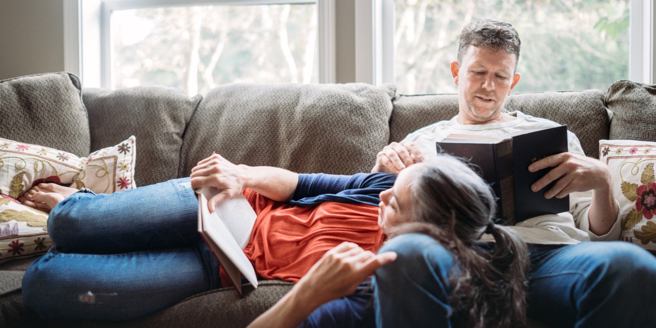 Couple reading books on sofa together