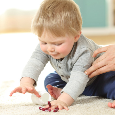 Baby reaching for pills on the floor.