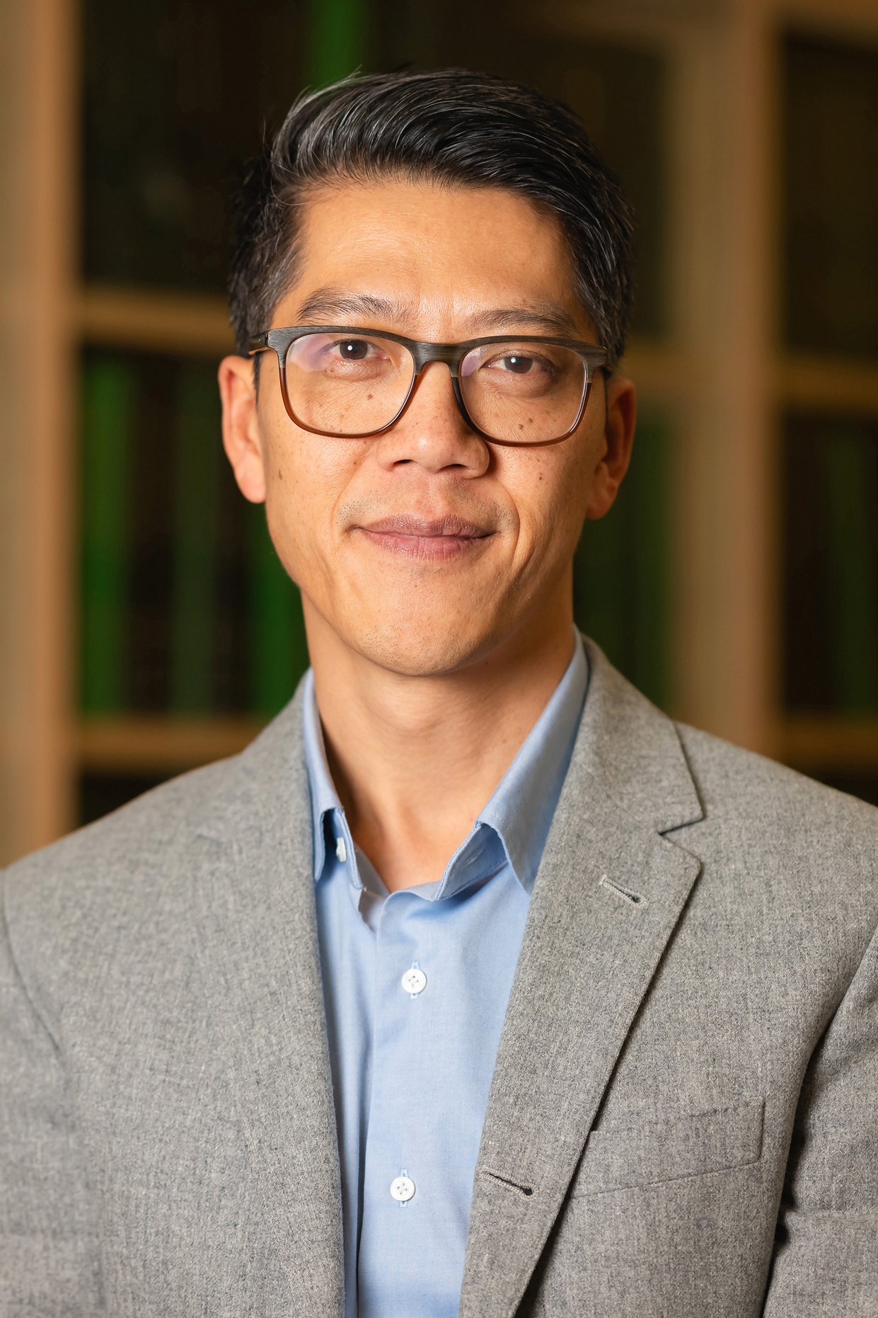 Henry An poses professionally in front of a bookshelf