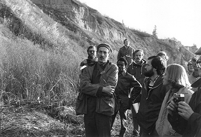 Charlie Stelck chatting with a group of geologists on a digsite.