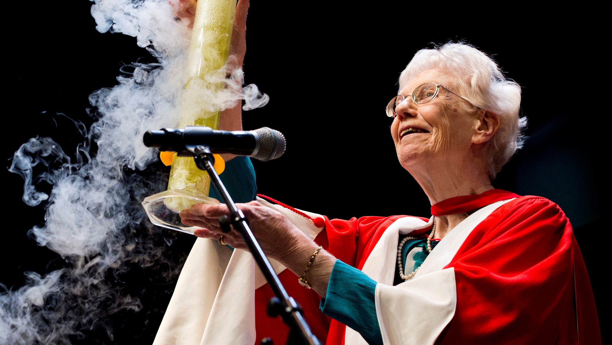 Margaret-Ann Armour holding a bubbling beaker aloft at a convocation ceremony