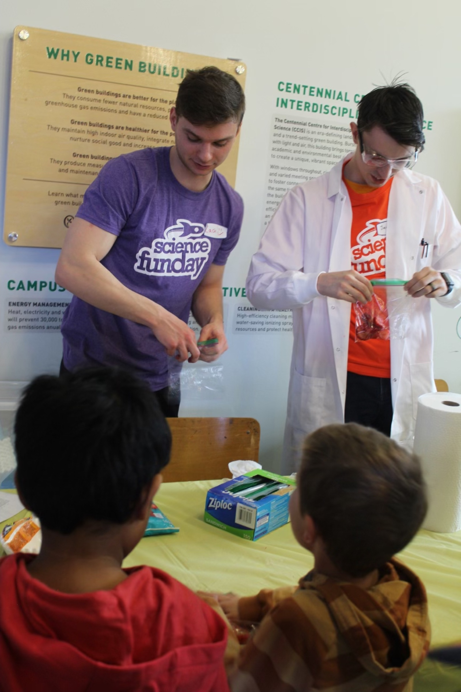 Student volunteers including a Science FUNday executive lead a demo isolating strawberry DNA for a group of engaged students.