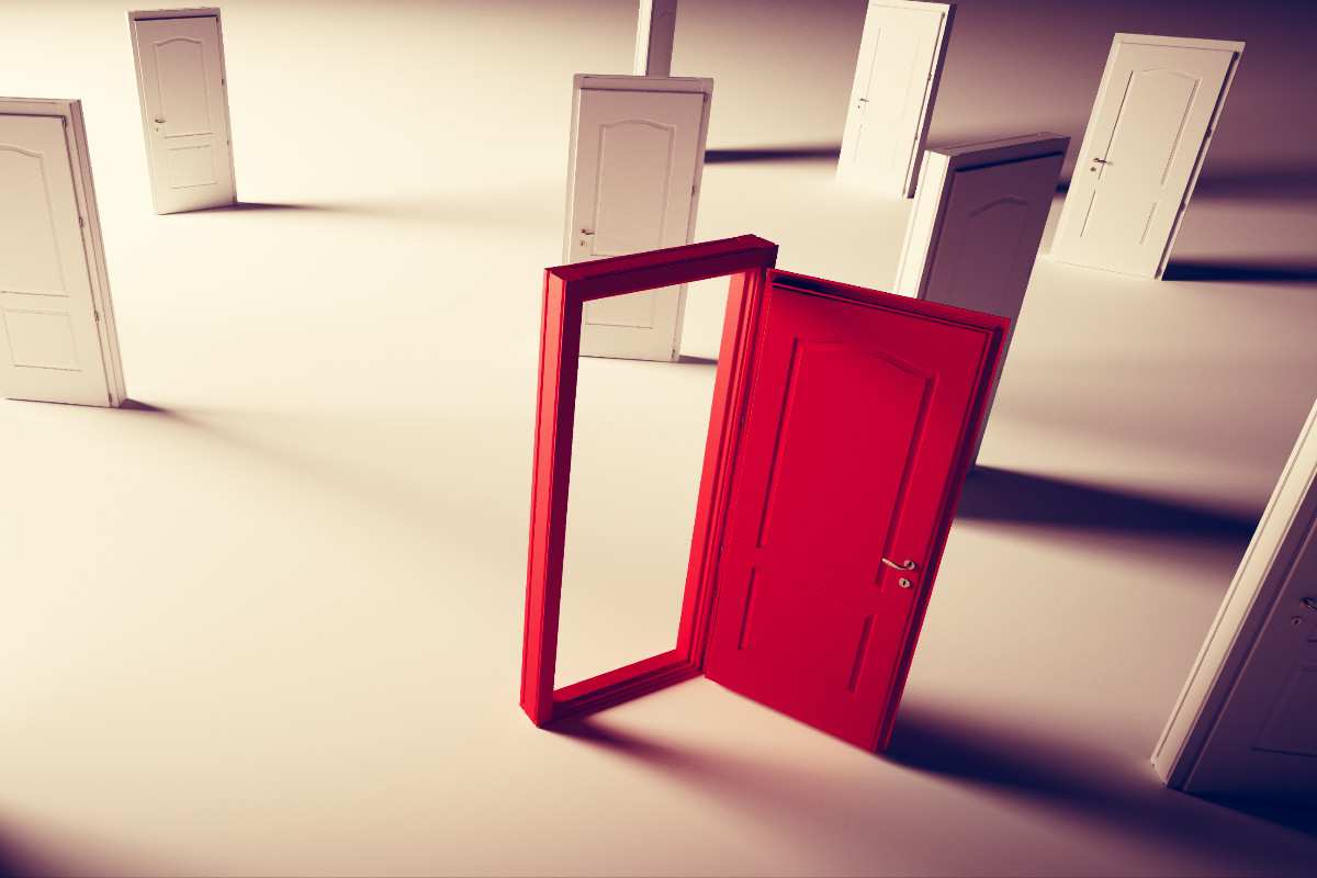 Several closed white doors stand in a featureless room. One doorframe is painted in vibrant red, and this door stands open.