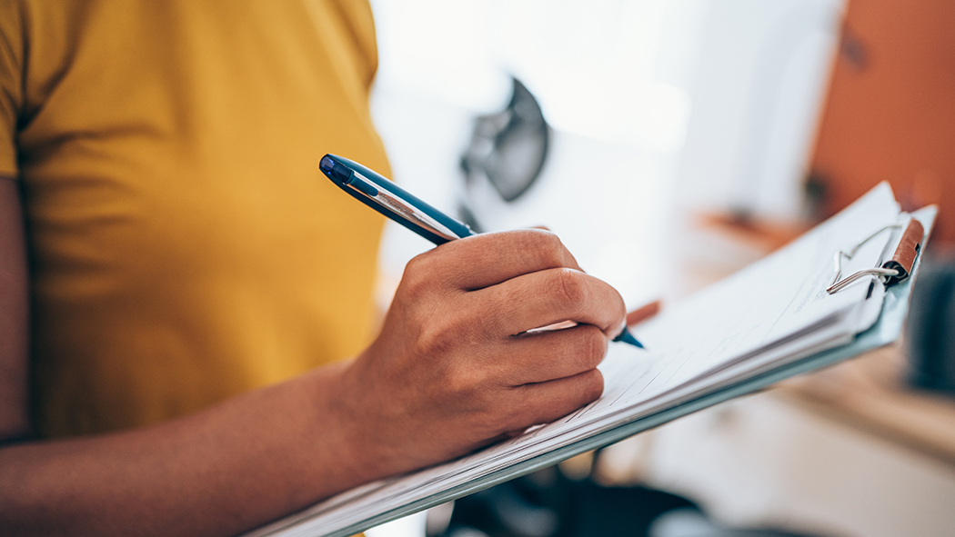 Person writing with clipboard