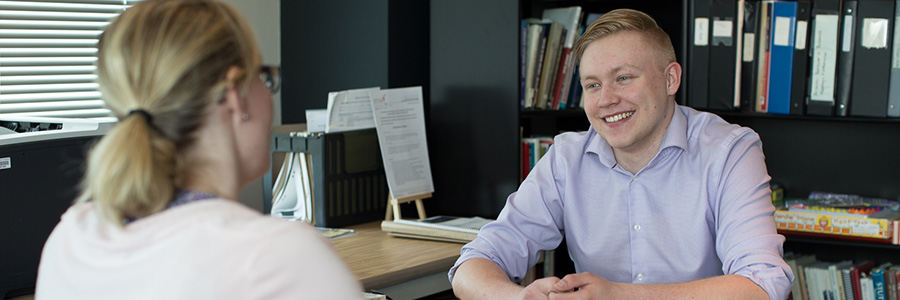 a man and woman sitting in an office talking