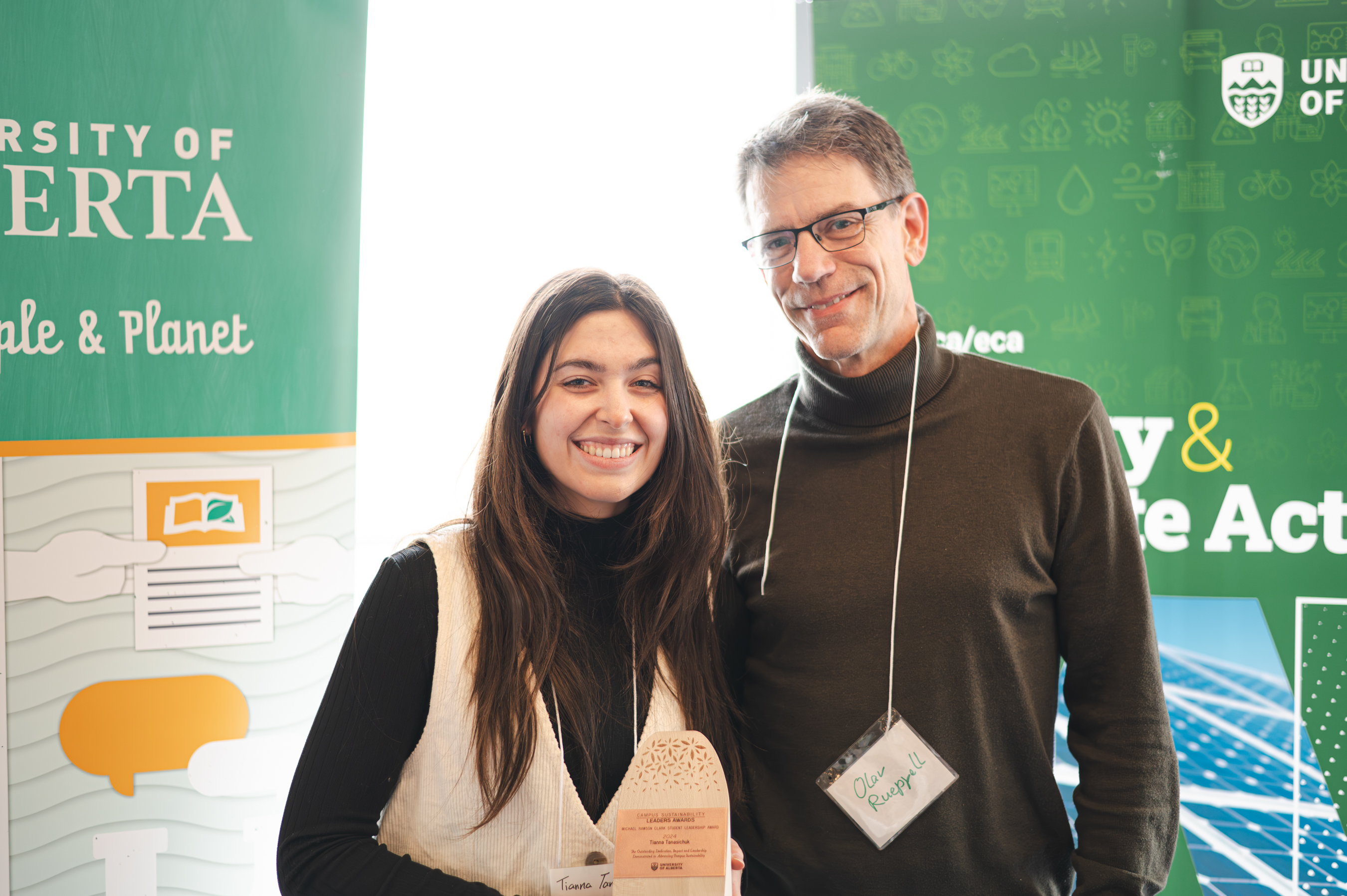 Tianna Tanasichuk smiling and holding her trophy, standing next to her principal investigator, Olav Rueppell.
