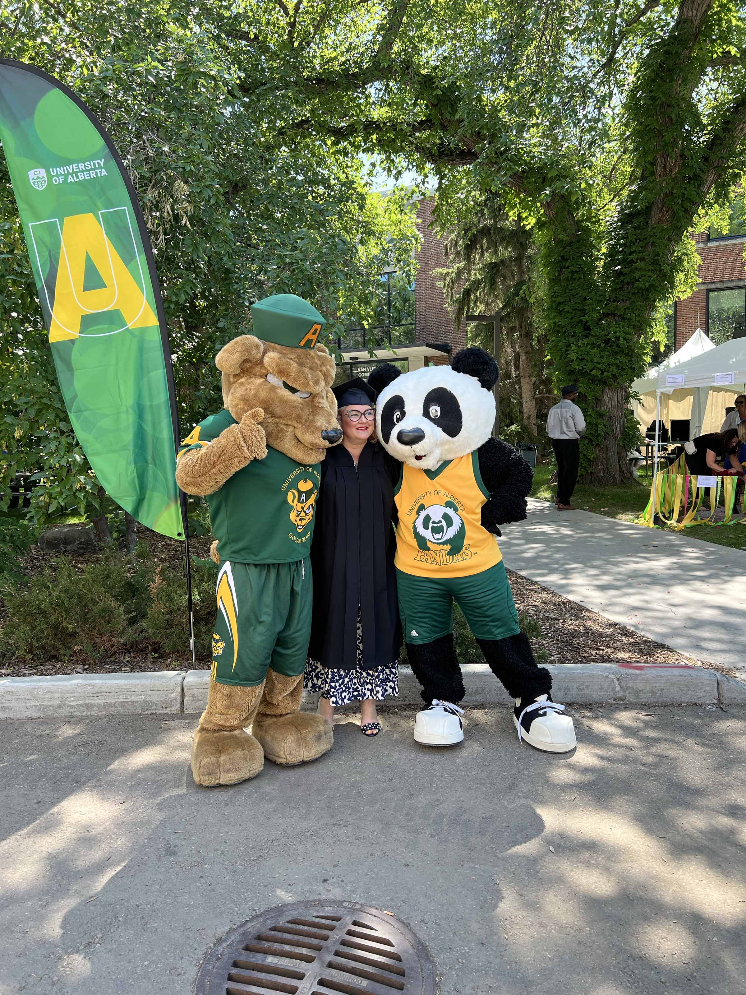 A graduate poses with Guba and Patches.