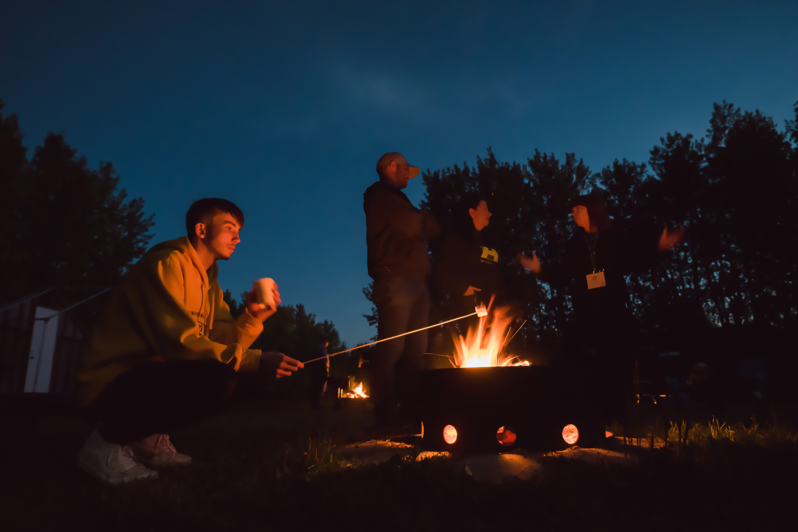 People enjoy hot chocolate around a fire at the Hesje Observatory at Miquelon Lake