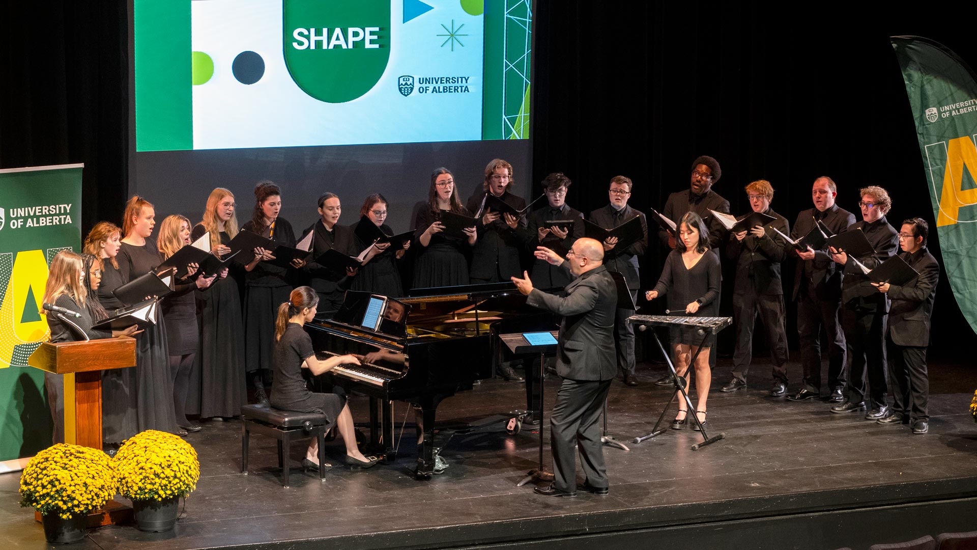 A choir performing with a conductor, pianist and xylophonist