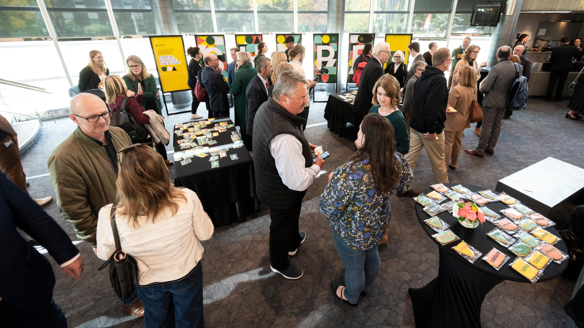 Members of the university community connect after the event in front of shaped cookies and posters spelling the word Shape