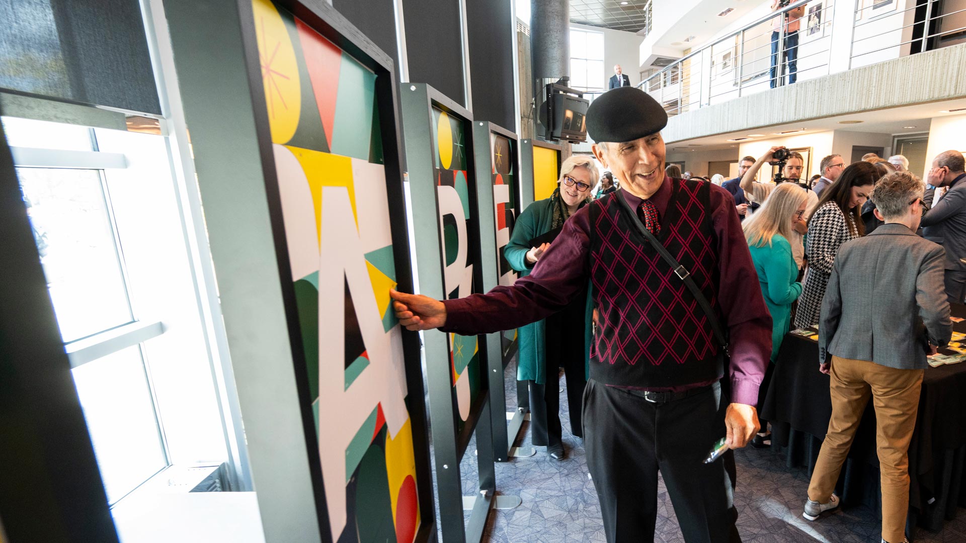 Elder Francis Whiskeyjack having just pasted a sticker onto a poster that is shaped like a letter A