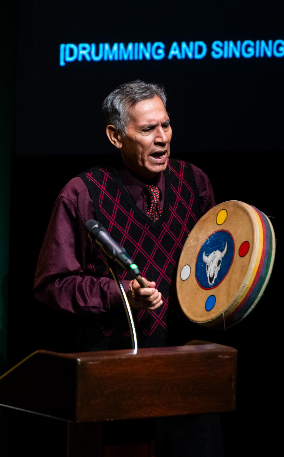 Elder Francis Whiskeyjack singing and playing the drum