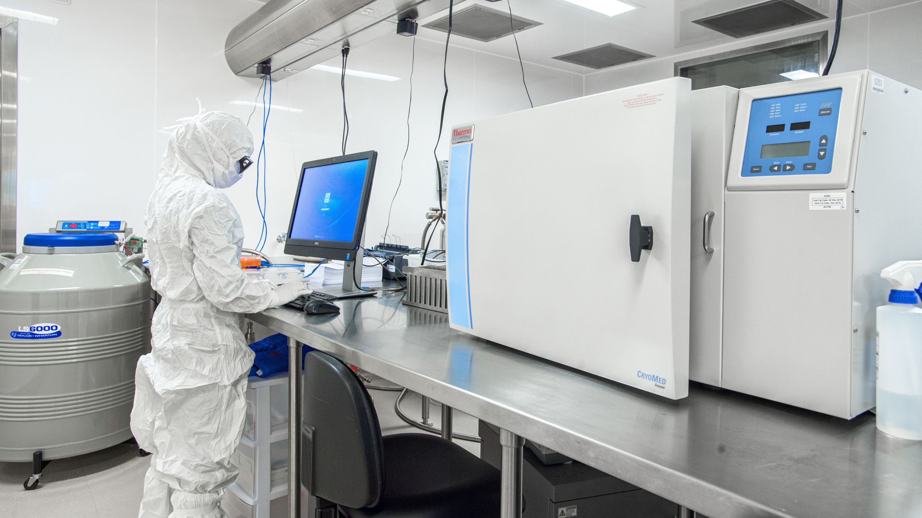 Person in PPE working at a computer in a research lab - University of Alberta