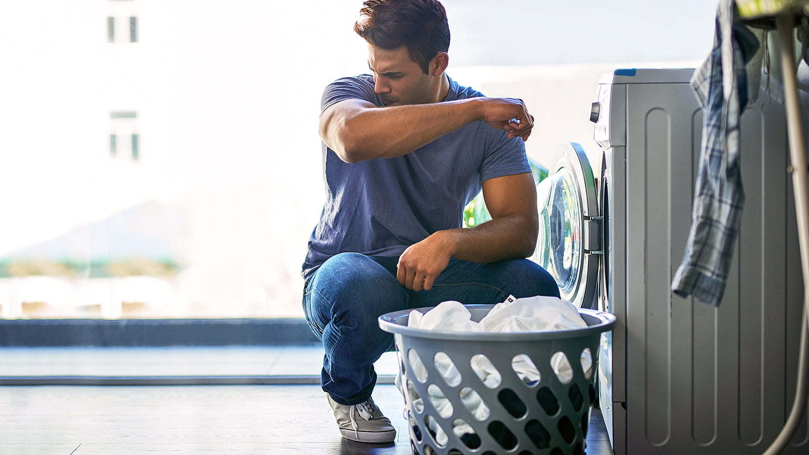Man with laundry basket in front of washing machine (Photo: Getty Images)