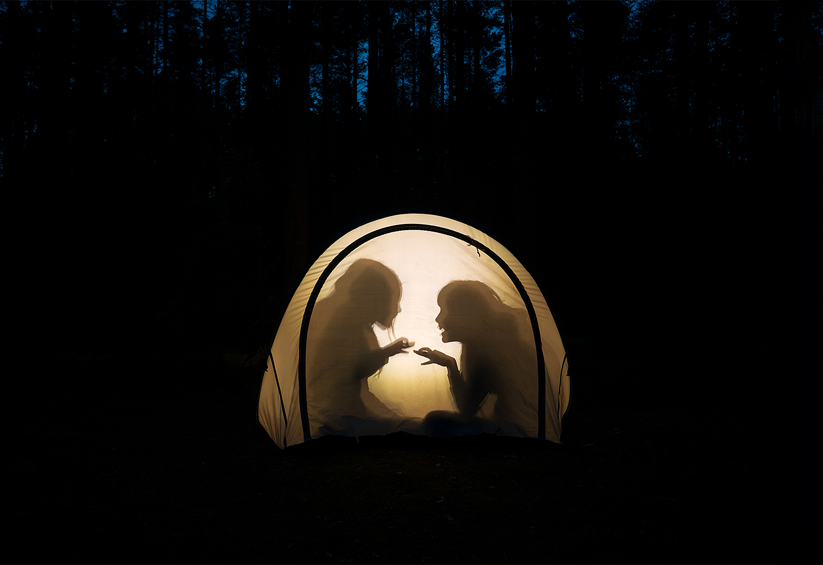 Children telling scary stories in a tent at night