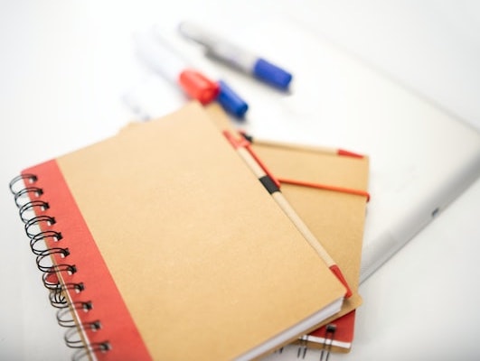 closeup of a notebook with pens and a tablet device